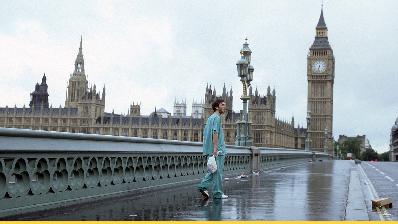 A lone survivor in hospital scrubs walks through an eerily deserted London near Big Ben in a haunting scene from 28 Days Later