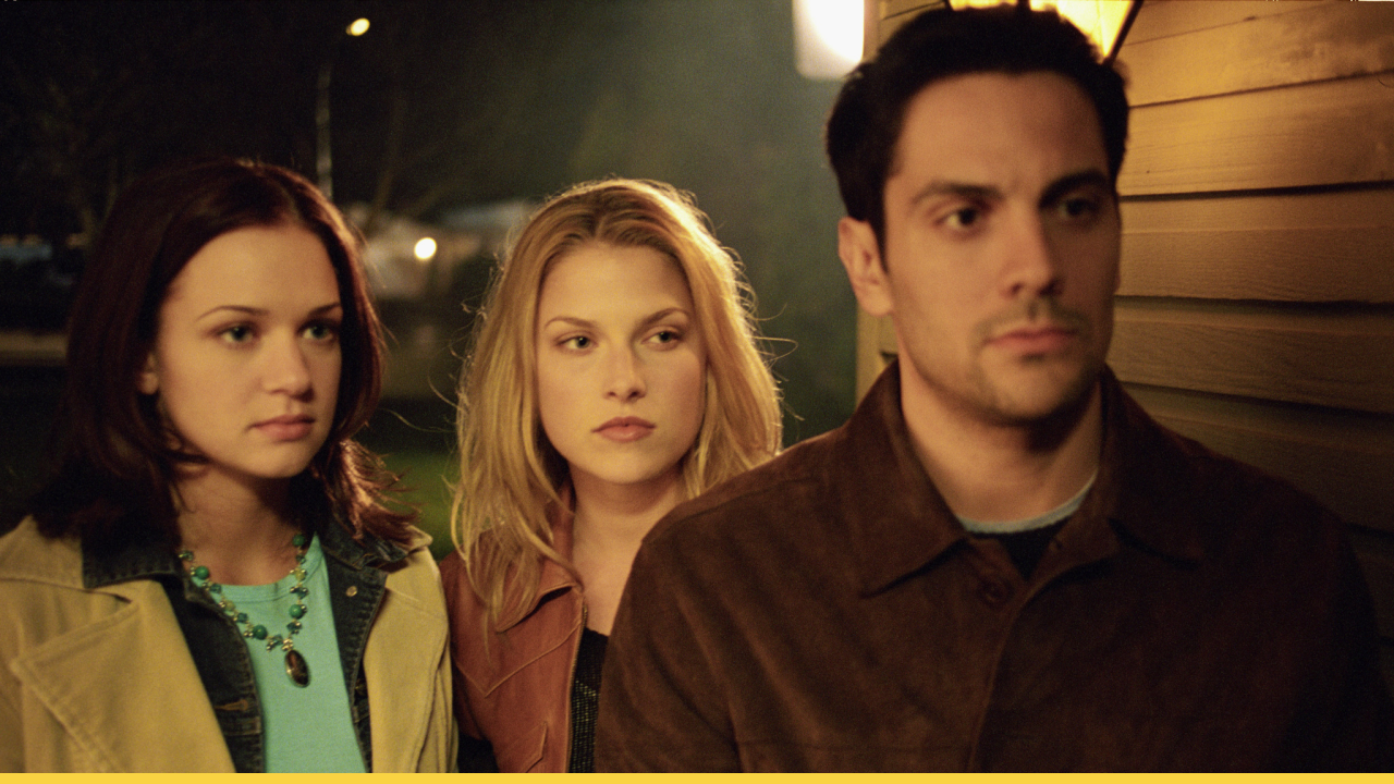 Three tense characters stand outside a house at night in a suspenseful moment from Final Destination 2