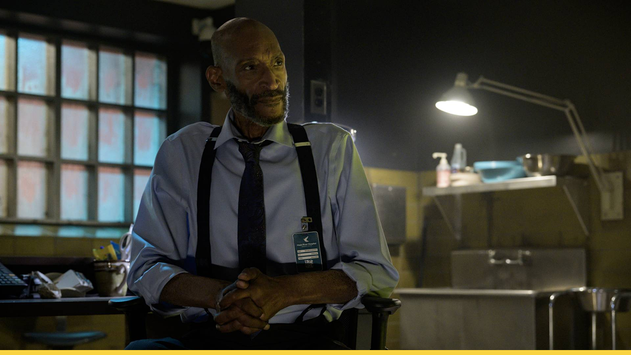 A mysterious man sits pensively in a dimly lit room, hinting at deeper secrets in Final Destination: Bloodlines