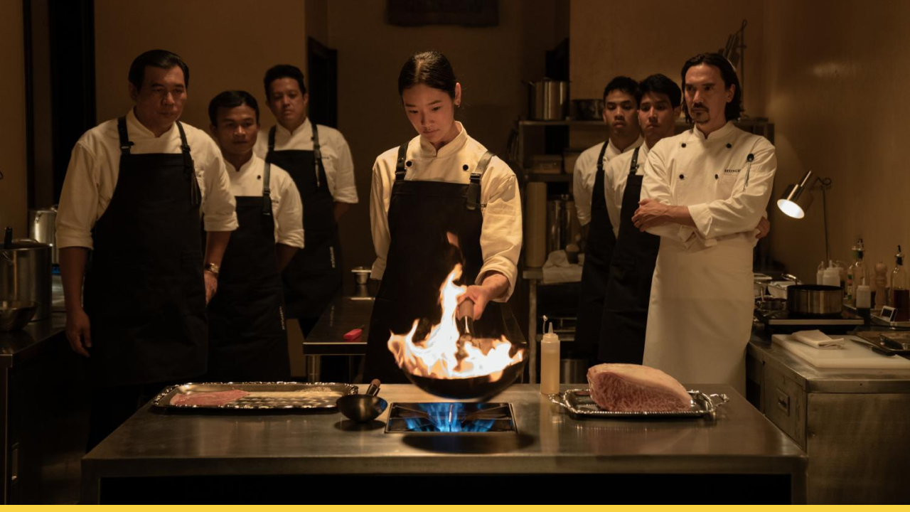 A young chef commands fire under watchful eyes in a high-stakes gourmet kitchen