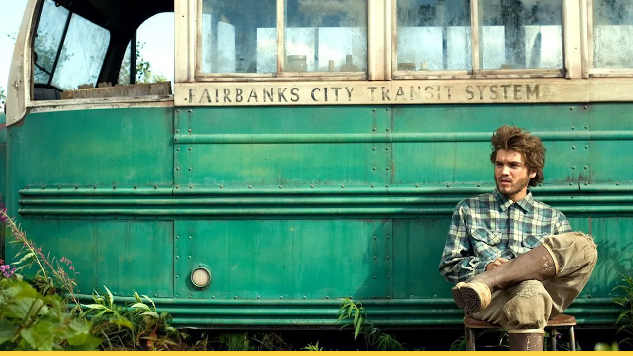 Christopher McCandless sitting by an abandoned green bus in the wilderness.