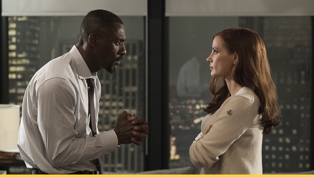 Idris Elba and Jessica Chastain in a dramatic scene from Molly's Game, having an intense conversation inside a high-rise office at night