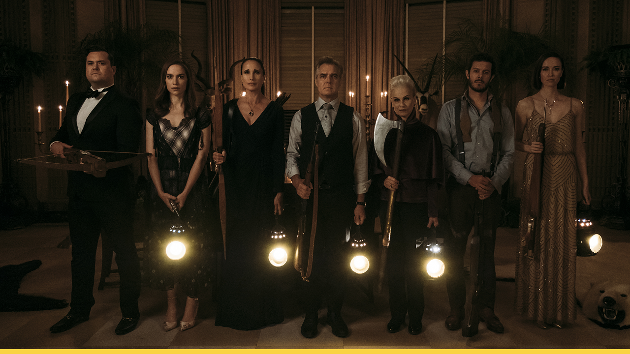 A wealthy family prepares for a deadly game, armed and ominous in a candlelit room