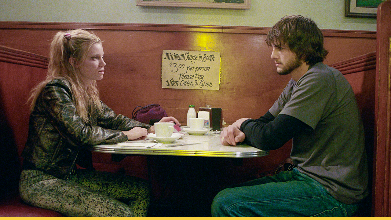 Two characters sit tensely across from each other in a diner in a pivotal scene from The Butterfly Effect.