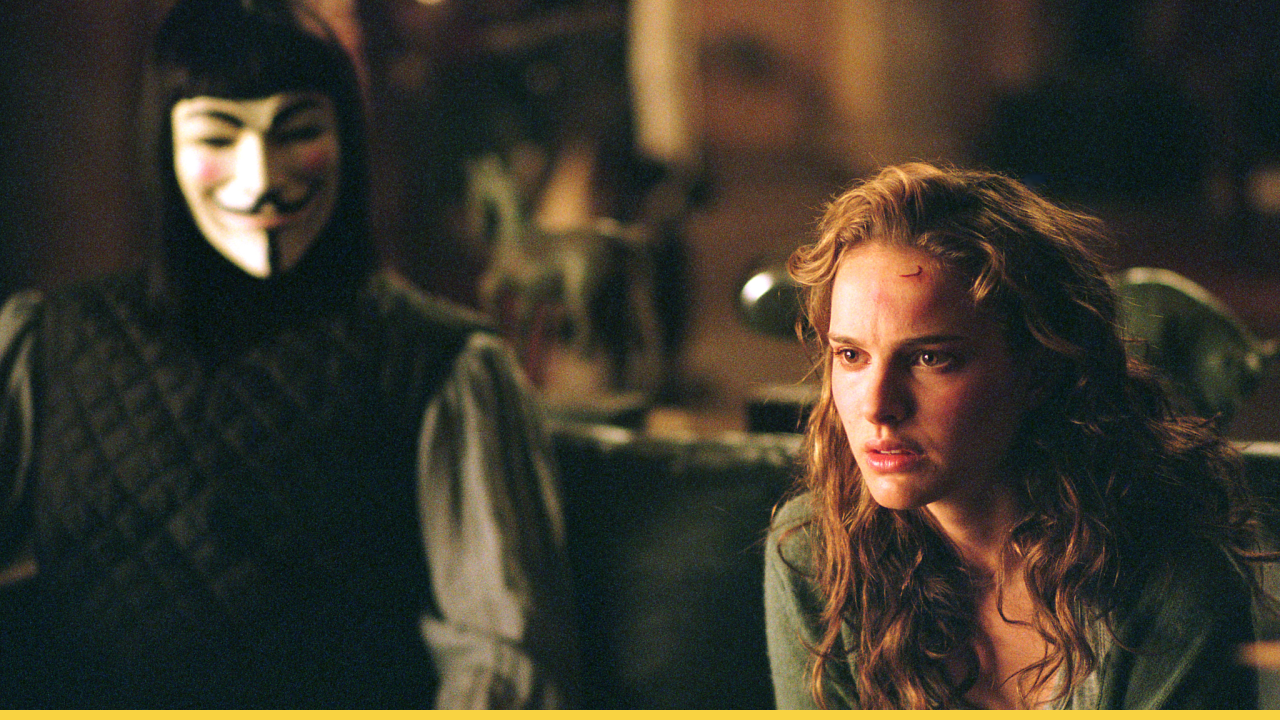 Evey Hammond sits visibly shaken as V watches silently behind her in a tense moment from V for Vendetta